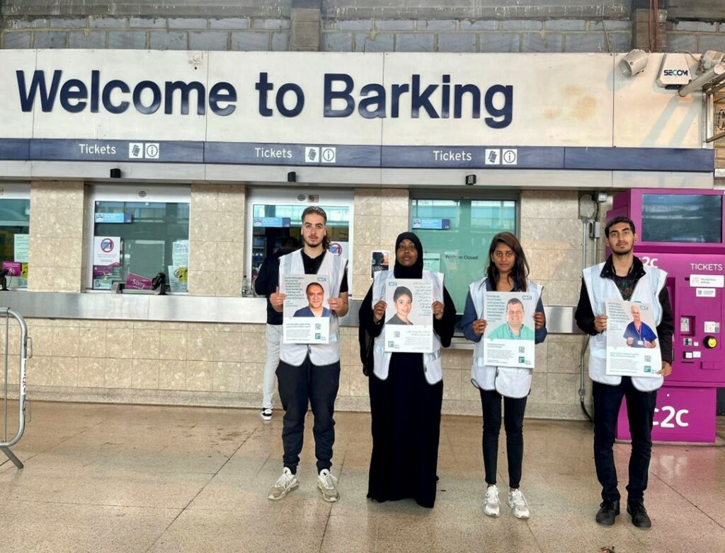 Volunteers of the NHS bowel cancer campaign at Barking Tube holding campaign graphics in several languages highlighting the benefits of using the screening programme. 