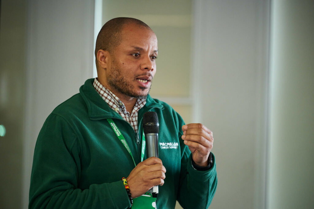 Lee, Engagement lead at Macmillan Cancer Services presents with a microphone in hand.