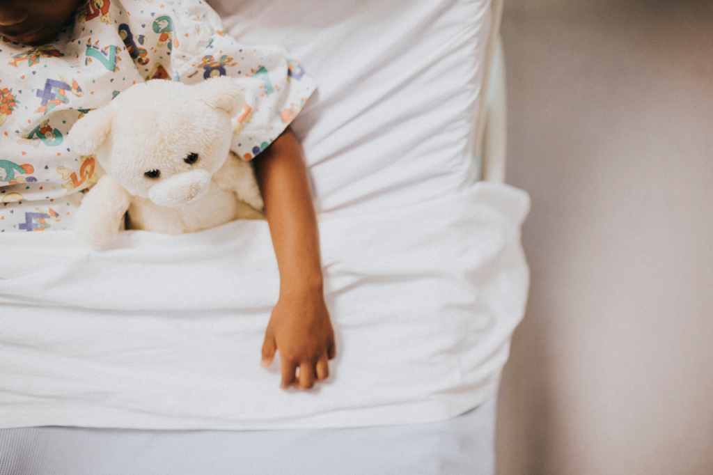 Child in hospital bed with teddy bear