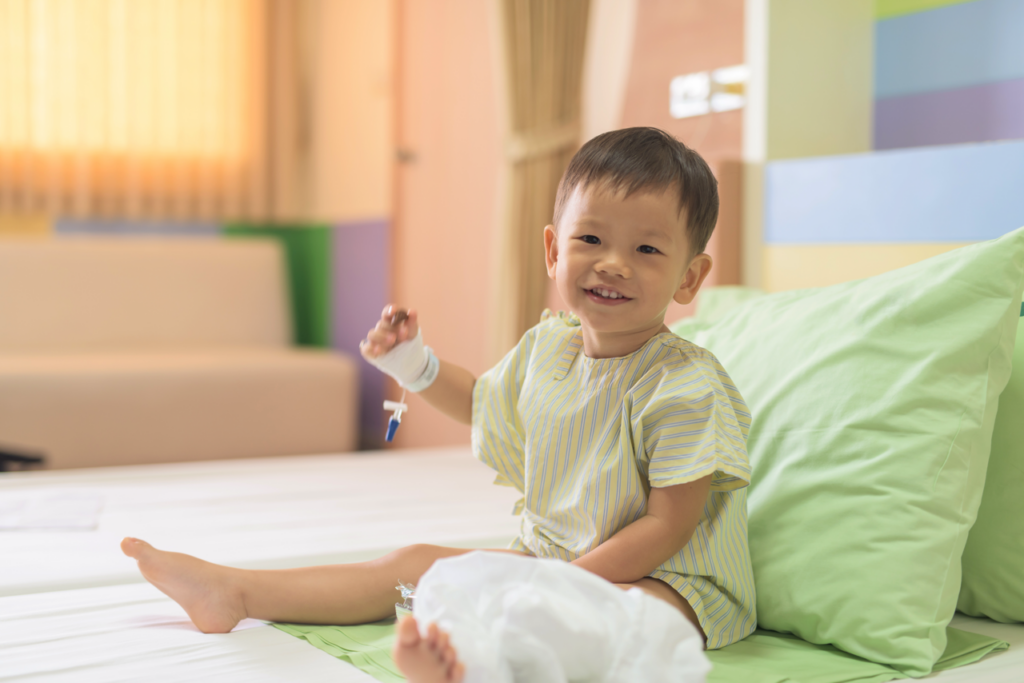 Smiling child on hospital bed with bandaged hand