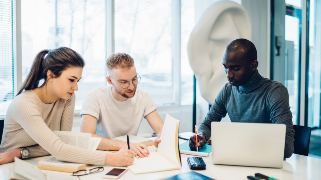 Three professionals working together at a desk.