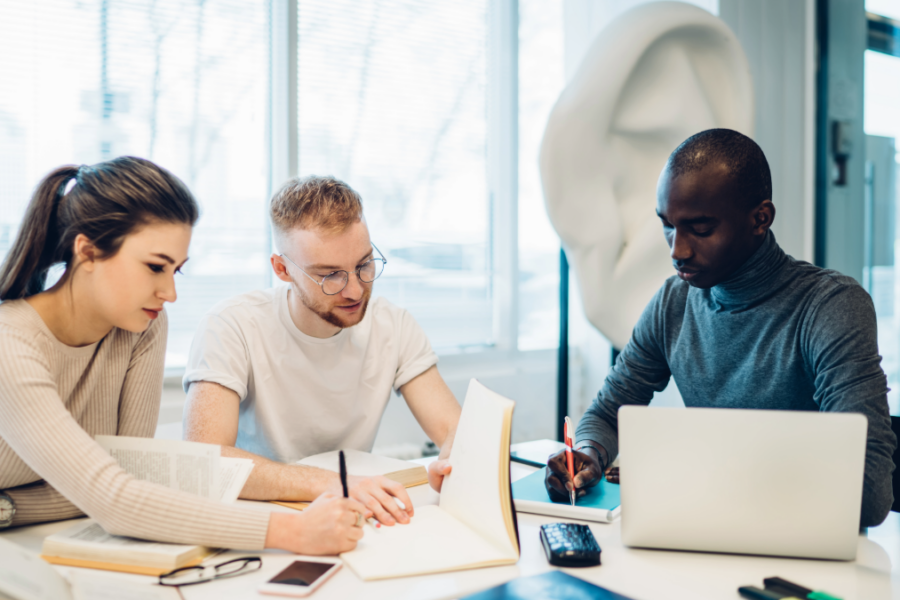 Three professionals working together at a desk.