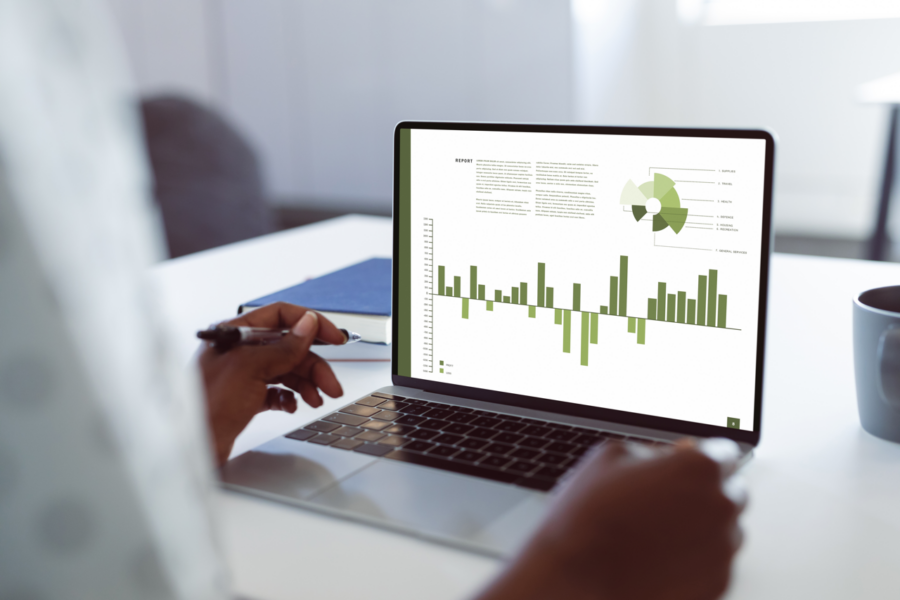 A laptop open with a report displayed on screen, with charts in shades of green