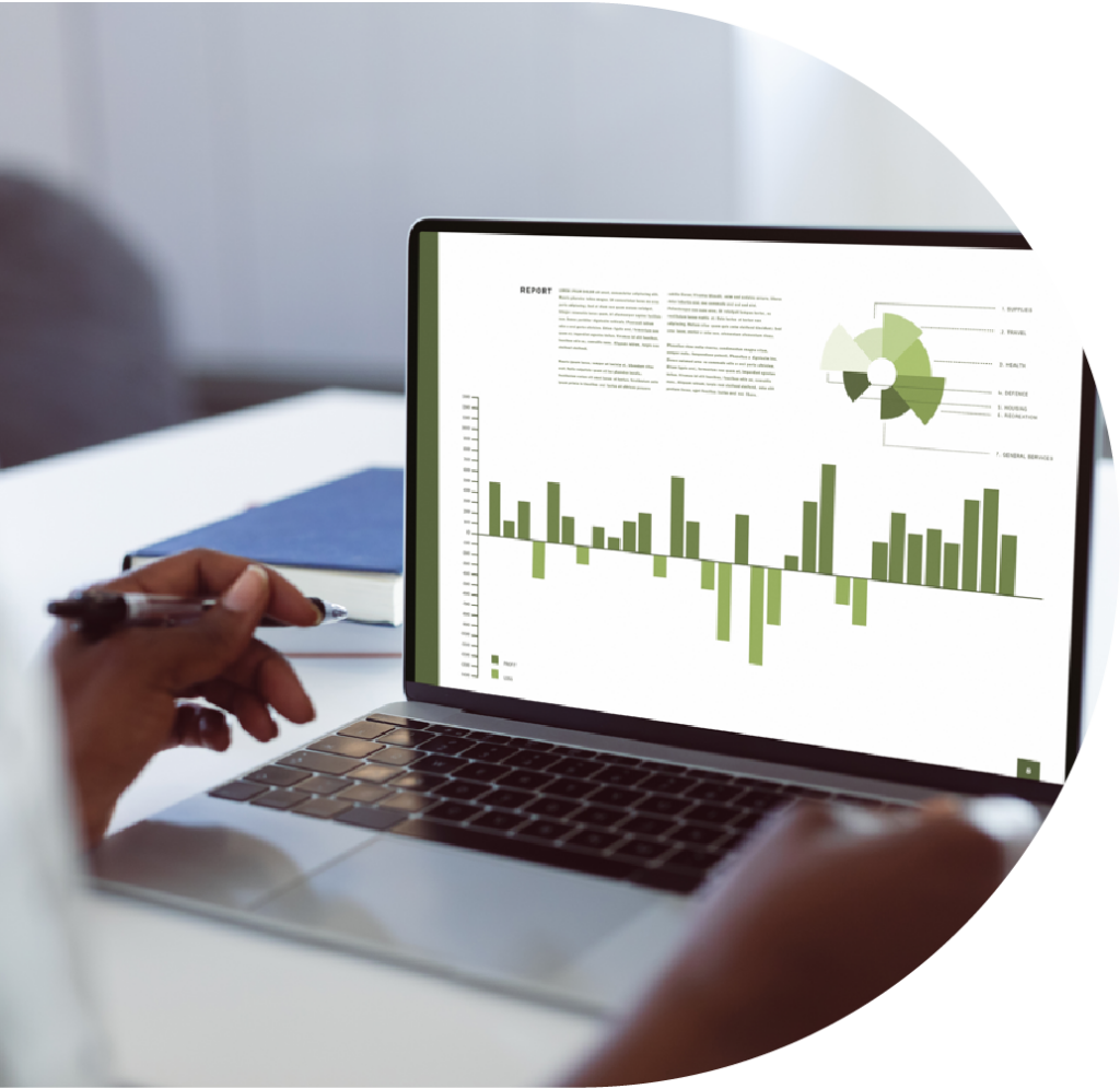 A laptop open with a report displayed on screen, with charts in shades of green