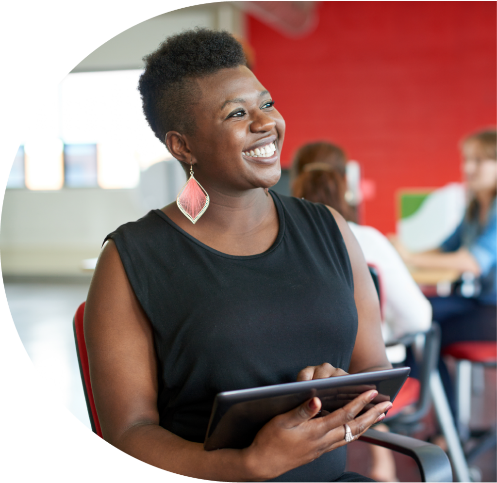 Smiling female presenting person holding a tablet and looking off camera