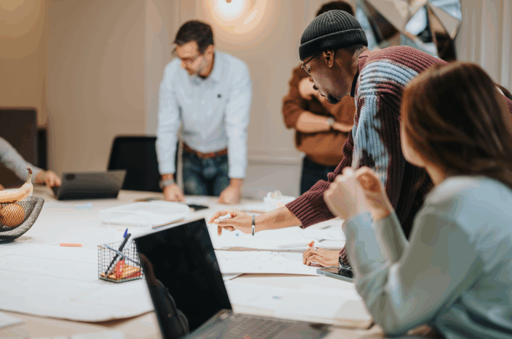 A diverse group of people around a large table with paper and pens