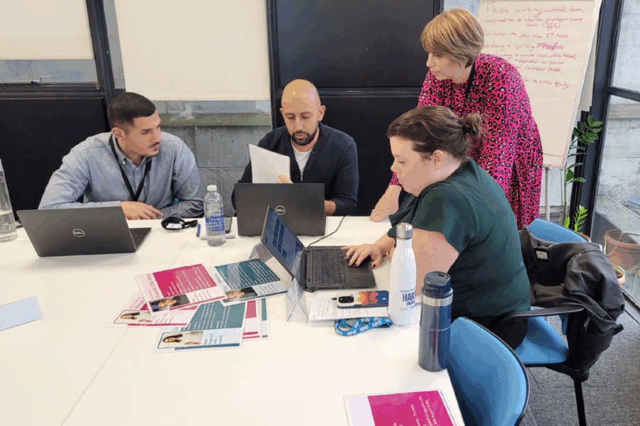 A group of people at a table with laptops and sheets of information taking part in a Line Management training course