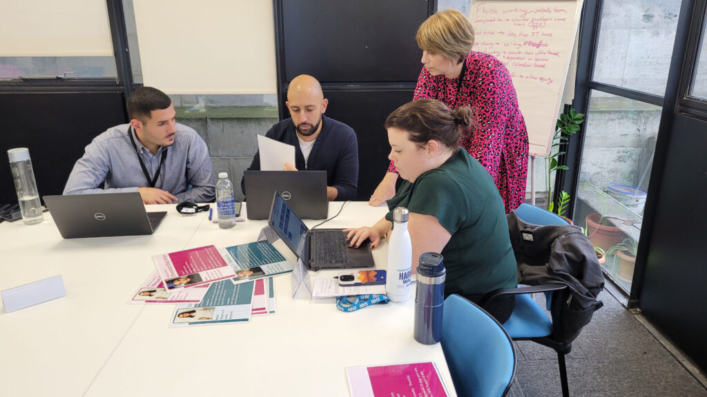 A group of people at a table with laptops and sheets of information taking part in a Line Management training course