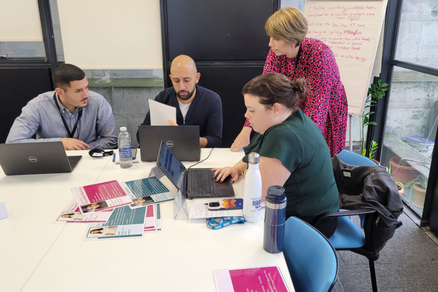 A group of people at a table with laptops and sheets of information taking part in a Line Management training course