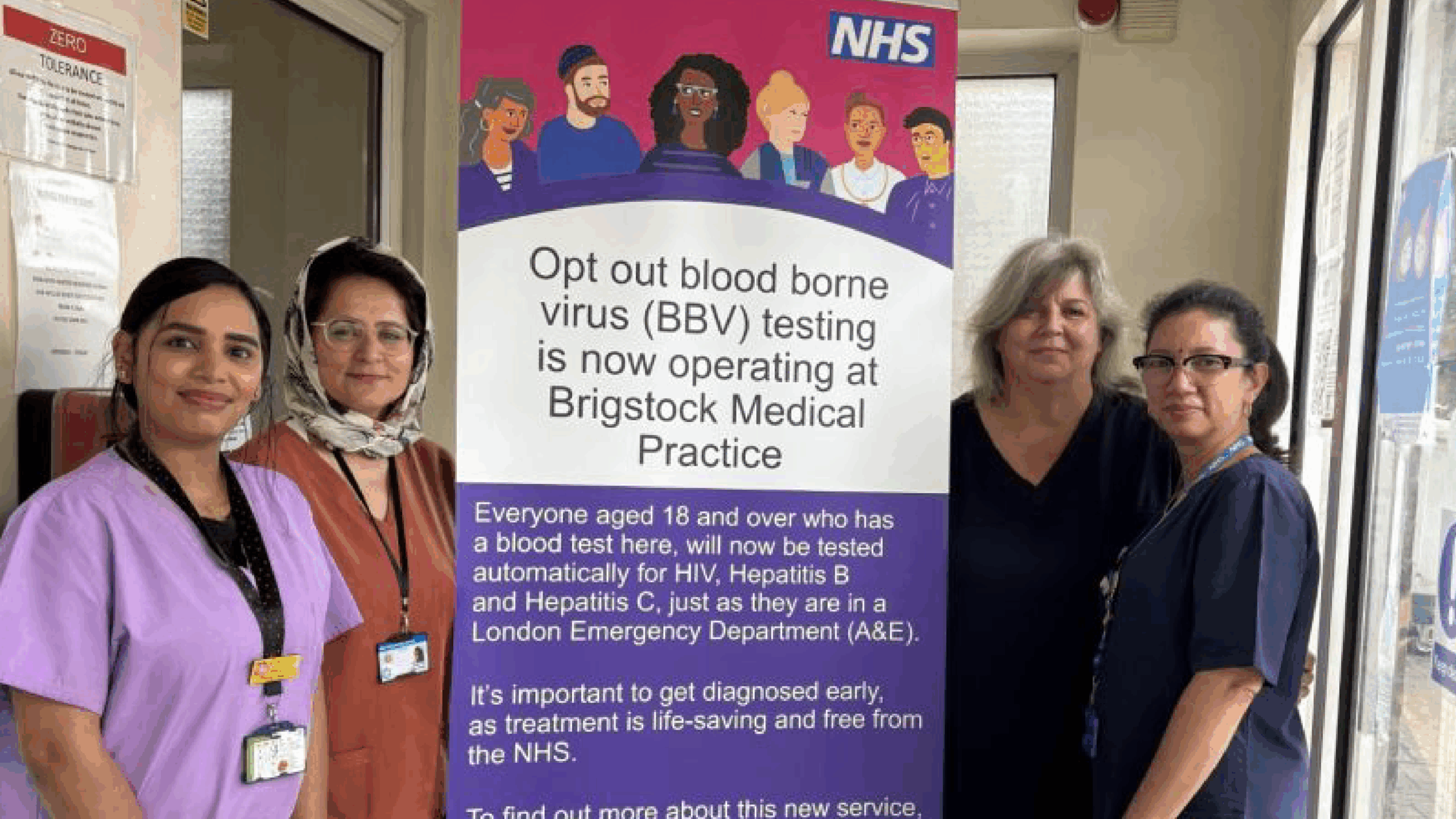 A group of female medical professionals stood next to a banner showcasing opt-out BBV testing