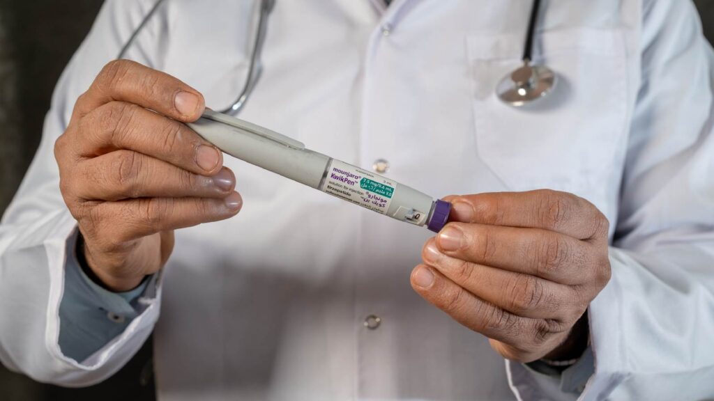 A medical practitioner holding a Mounjaro pen