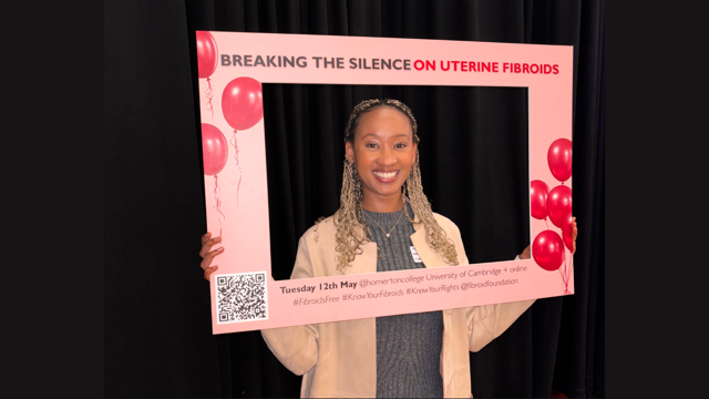 Natasha Wainaina holds a pink awareness frame reading ‘Breaking the Silence on Uterine Fibroids’ at an event promoting education and discussion about uterine fibroids.
