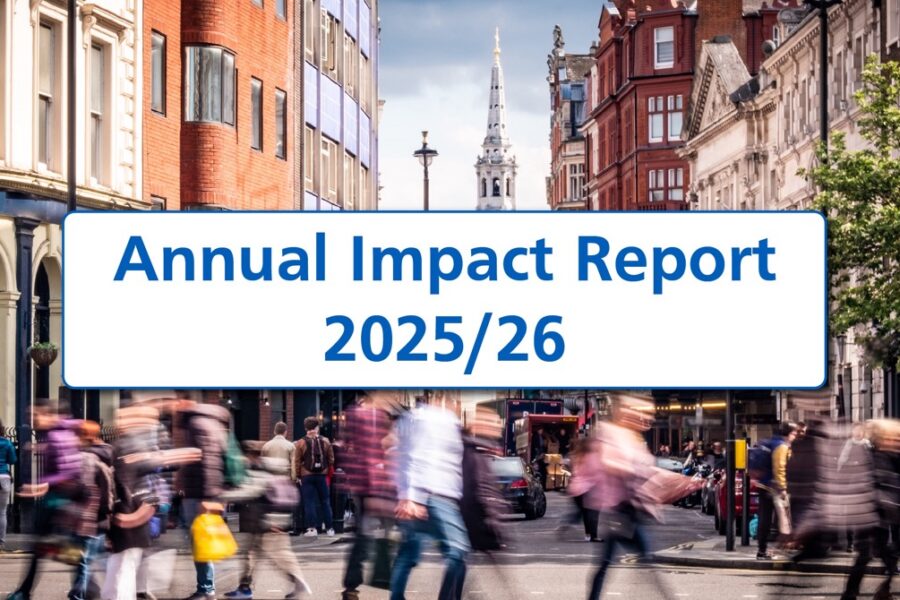A wide banner image showing a busy London street with blurred pedestrians crossing in the foreground and historic city buildings lining both sides. The spire of St Martin-in-the-Fields rises in the distance beneath a cloudy sky. A large white rounded rectangle with a blue border overlays the centre, displaying the title ‘Annual Impact Report 2025/26’ in bold blue text.