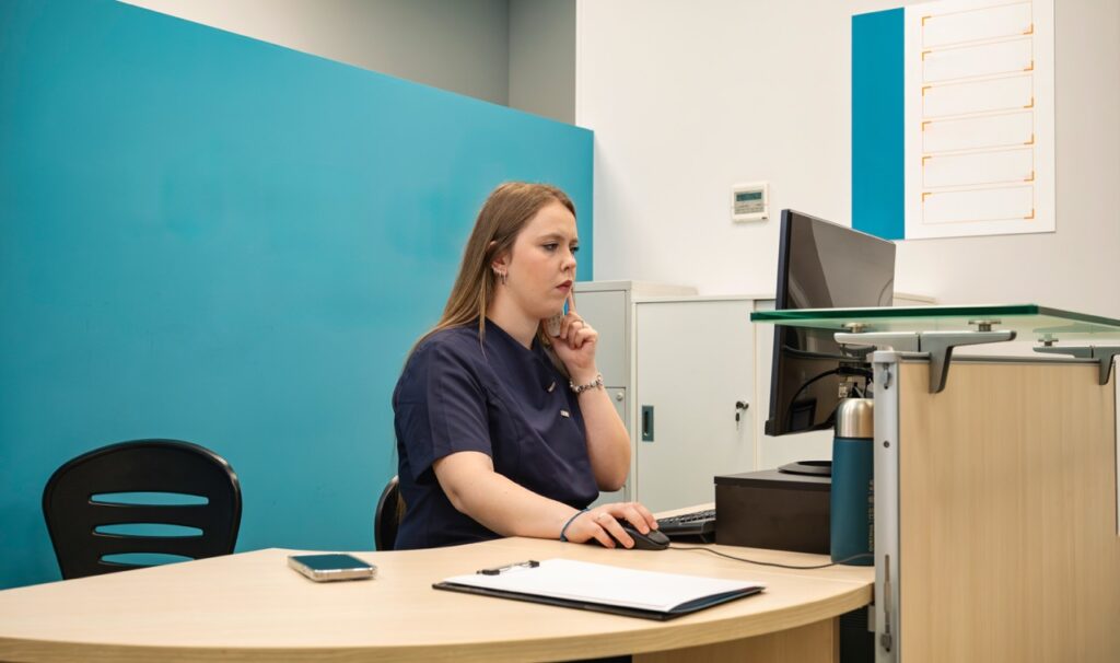 A member of clinic administrative staff working at a computer.