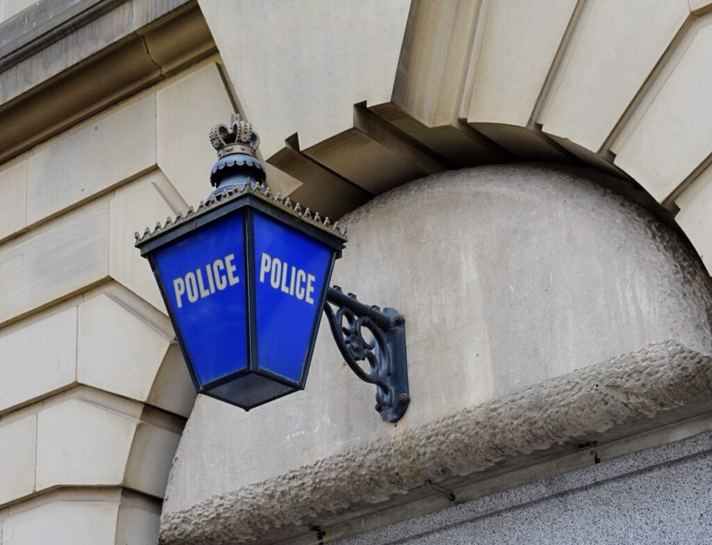 Traditional blue police lantern mounted on the exterior of a stone building.