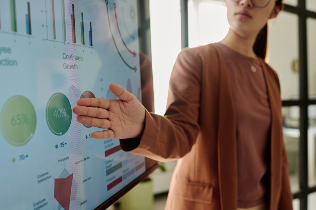 A person presenting data charts and metrics on a large screen to colleagues in a modern office